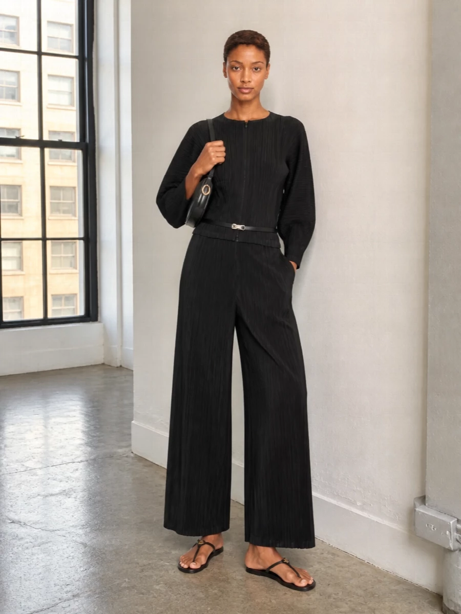 An all-black Pleats Please column keeps the focus on line and movement, the micro-pleats reading sculptural rather than soft. Flat Prada sandals, a curved Patou shoulder bag and a slim Totême belt introduce subtle structure and hardware, so the outfit feels considered enough for art openings yet relaxed for warm evenings. The result is modern, minimal and quietly assured from every angle.
