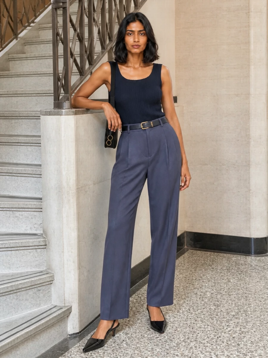 Slate-navy pleated tailoring meets a sculpted knit tank for a clean, elongated column that feels composed without trying. A navy belt and black kitten-heel slingbacks refine the proportions, while a sharply cut Alaïa shoulder bag adds just enough structure and shine for formal dinners or discreet evening meetings.