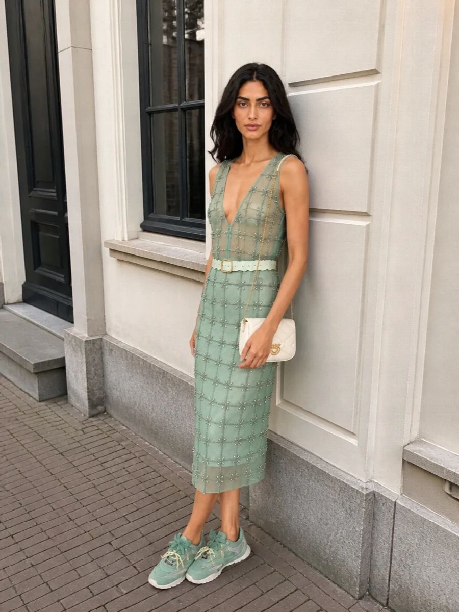 A head-to-toe mint beaded set turns the sheer tank into a modern party twinset, all shimmer and soft structure with that deep V back as the focal point. Sage runners keep it playful and grounded, so the sparkle reads fresh rather than formal. An ivory mini cross-body and scalloped mint belt finish the palette with light, romantic polish that still feels easy for rooftop drinks or late dinners.
