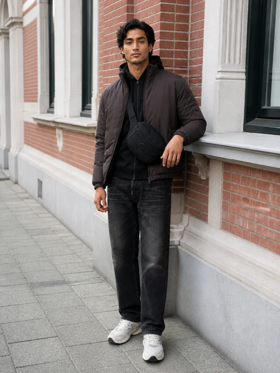 Herno’s dark taupe padded jacket sits over an all-black Y-3 hoodie and washed Haikure denim for a calm, city-ready base. New Balance runners in warm off-white cut the darkness just enough, while a compact C.P. Company crossbody finishes the technical, sport-slanted mood without sacrificing quiet polish.