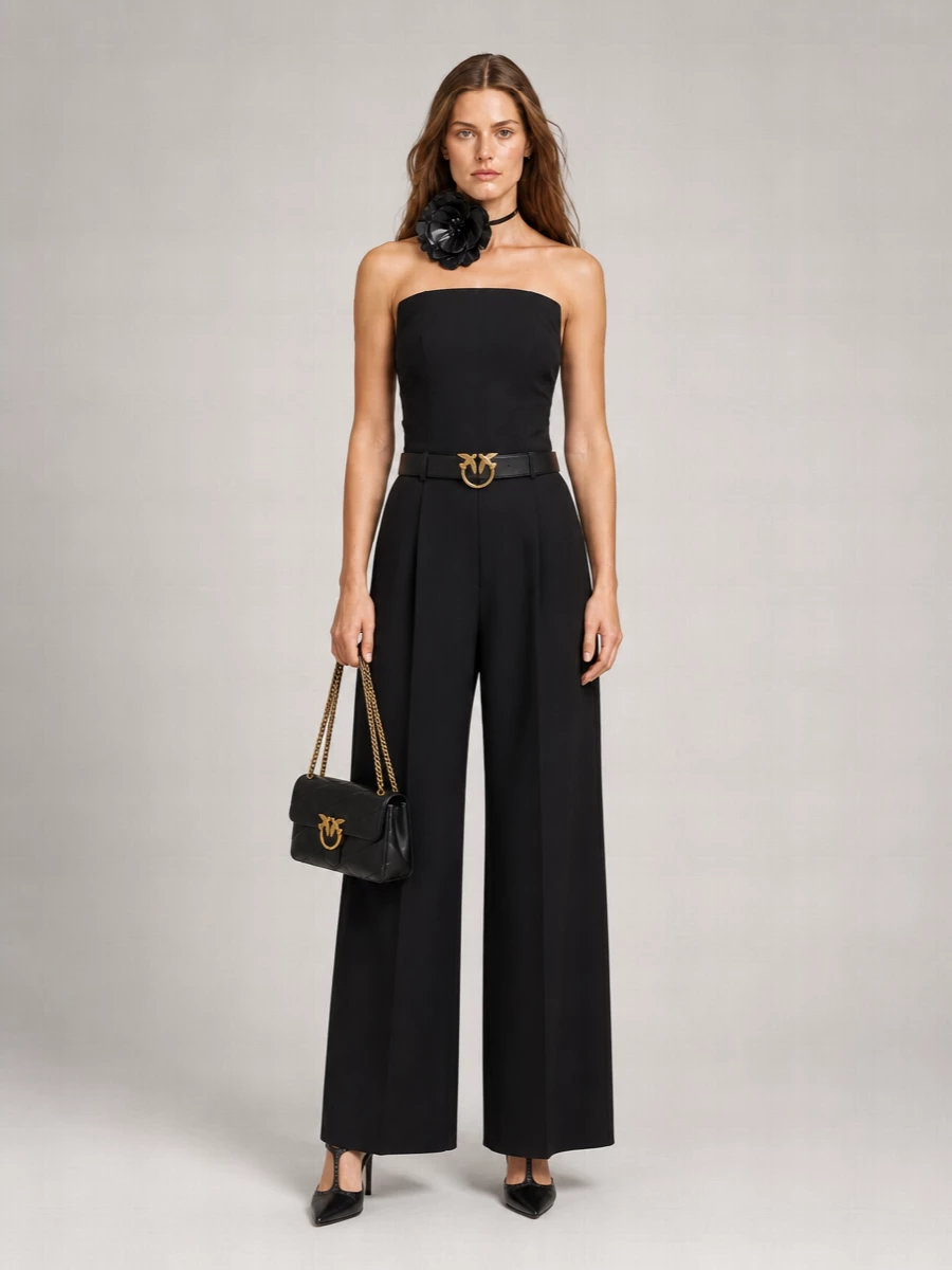 An all-black, high-waisted wide leg anchors the strapless top’s sculpted drama, keeping the silhouette long, fluid and precise. Pointed black heels and a quilted gold-chain shoulder bag stay within the same Italian-after-dark language, giving the floral neck detail and chain belt space to shine. It is a sharp, confident evening edit that feels modern, romantic and unapologetically polished from every angle.