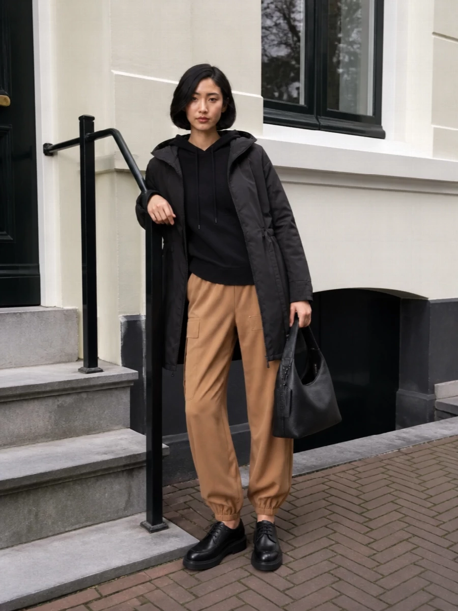 I’m anchoring this with the top and bottom route rather than a dress so the parka can sit in its natural habitat: relaxed, urban layering with a utility edge. The black hooded knit and coat create a quiet, elongated column, while the camel cargo trouser brings warmth and an intentional nod to function. Chunky lace-up derbies and a structured black hobo keep it all firmly in the quietly luxurious city-casual space, ready for errands, travel days or low-key office Fridays.
