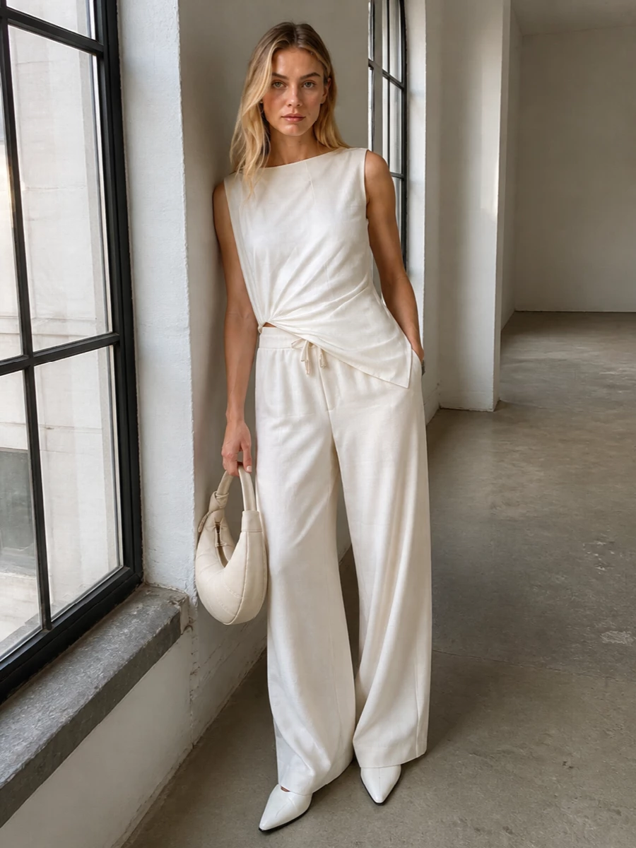 This look leans into a pure, tonal ivory story: fluid Jacquemus wide-leg trousers paired with the draped asymmetric blouse create an elongated, quietly sensual silhouette. Sharp pointed flats keep the line clean but wearable, while the sculpted hobo bag adds just enough structure for an elevated city evening or gallery dinner without disturbing the ease of the ensemble.