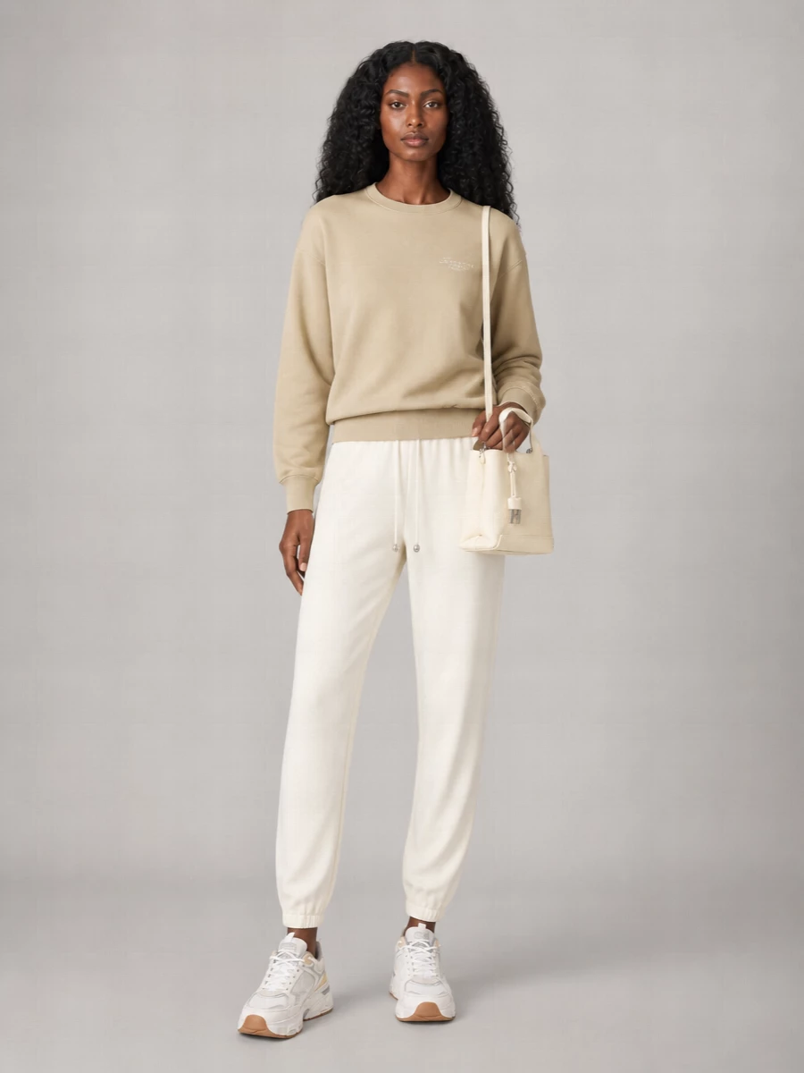 A sand-toned Givenchy sweatshirt and fluid ivory joggers build a soft, tonal base around the chunky runners. The mix feels relaxed yet intentional, with quiet branding and clean lines doing the work. The creamy Hogan mini tote adds just enough structure and polish while keeping the mood firmly in modern sport minimalism.
