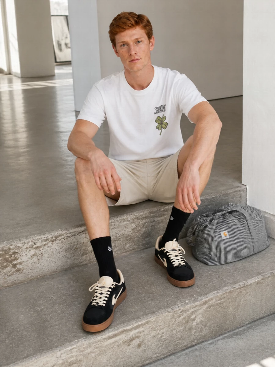 Carhartt WIP’s clover tee and light beige cargo shorts hit that easy skate‑meets‑utility register, keeping the palette bright while the proportions stay relaxed and practical. Black and cream Off-White sneakers ground everything with a graphic, low‑profile finish, and the striped tote plus subtle logo socks round it out for city days when you want things soft, simple and ready to move.