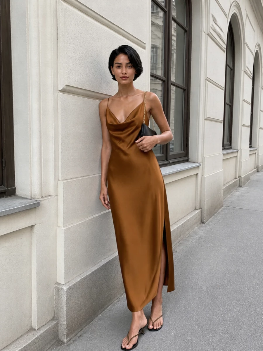 The caramel satin slip dress and sculptural thong heels create a long, liquid line in warm neutrals that feels modern and understatedly sensual. I chose the dress path here because one strong column works better with these directional sandals than breaking the body with separates. A slim black baguette adds just enough contrast and hardware to ground it for night without diluting the minimalist mood.
