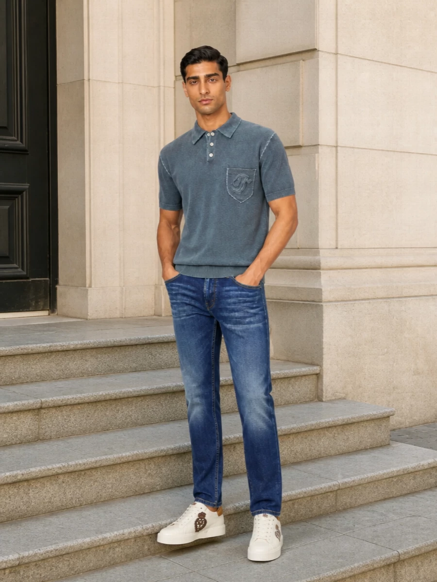 Dolce&Gabbana’s crest sneaker pairs with a slate blue Dsquared2 knit polo and slim indigo denim for a clean Italian mix of street and quiet luxury. The palette stays in soft blues and creams so the gold crest and subtle textures can do the talking, giving you a smart casual outfit that moves easily from daytime city errands to dinner on a terrace.