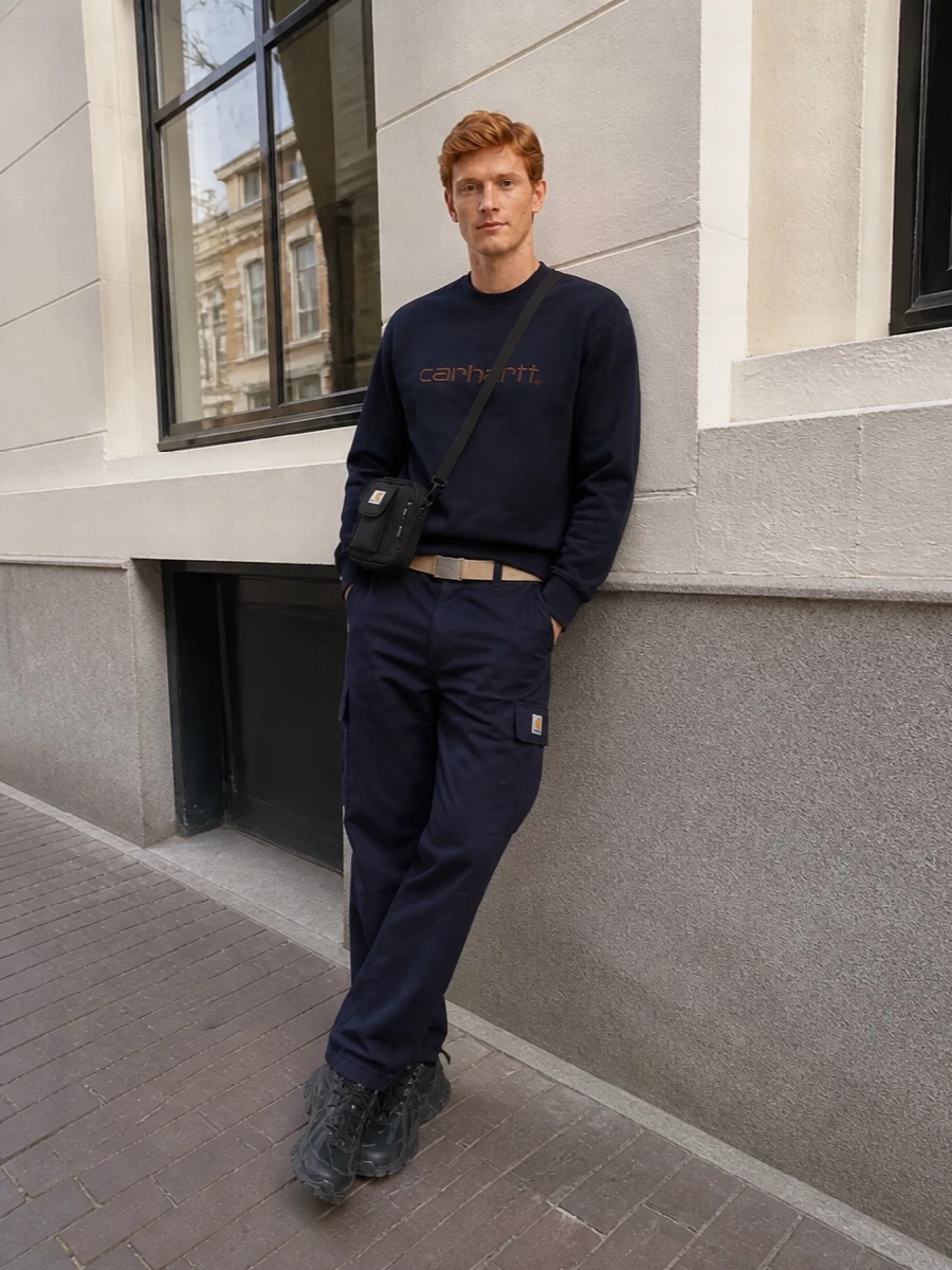 Deep navy cargos and a matching Carhartt crew keep this tight and graphic, all about clean lines and utility details. Technical black runners and a compact crossbody finish it with practical, city-ready energy.