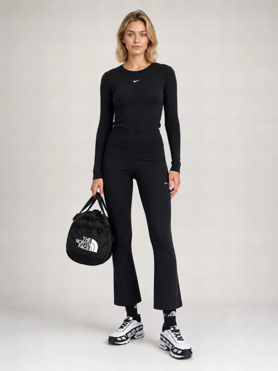 A tight black-on-black Nike base with a slight flare at the hem keeps the silhouette lean but not basic. The monochrome runners and graphic socks pick up the Swoosh details and add a considered sport edge. The compact duffle finishes it with a practical, technical note that still feels city-ready.