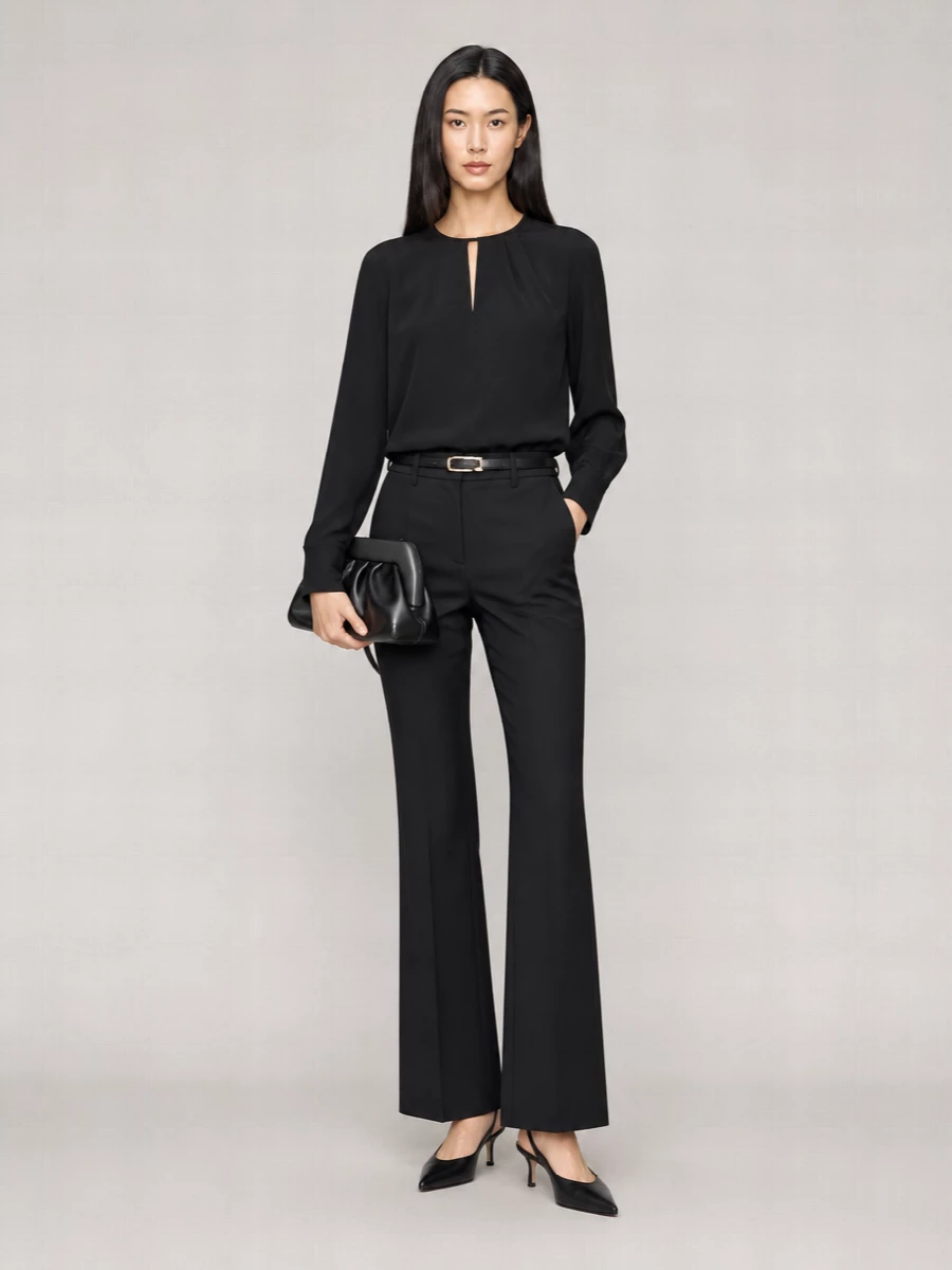 A pure black column of tailoring creates a long, uninterrupted line that reads considered and quietly powerful. The soft drape of the blouse offsets the precision of the high-waisted flared trouser, while the pointed slingbacks and sculpted clutch keep the finish sharp enough for a boardroom afternoon that turns into dinner. The slim belt is the only punctuation, adding structure without disturbing the restraint.