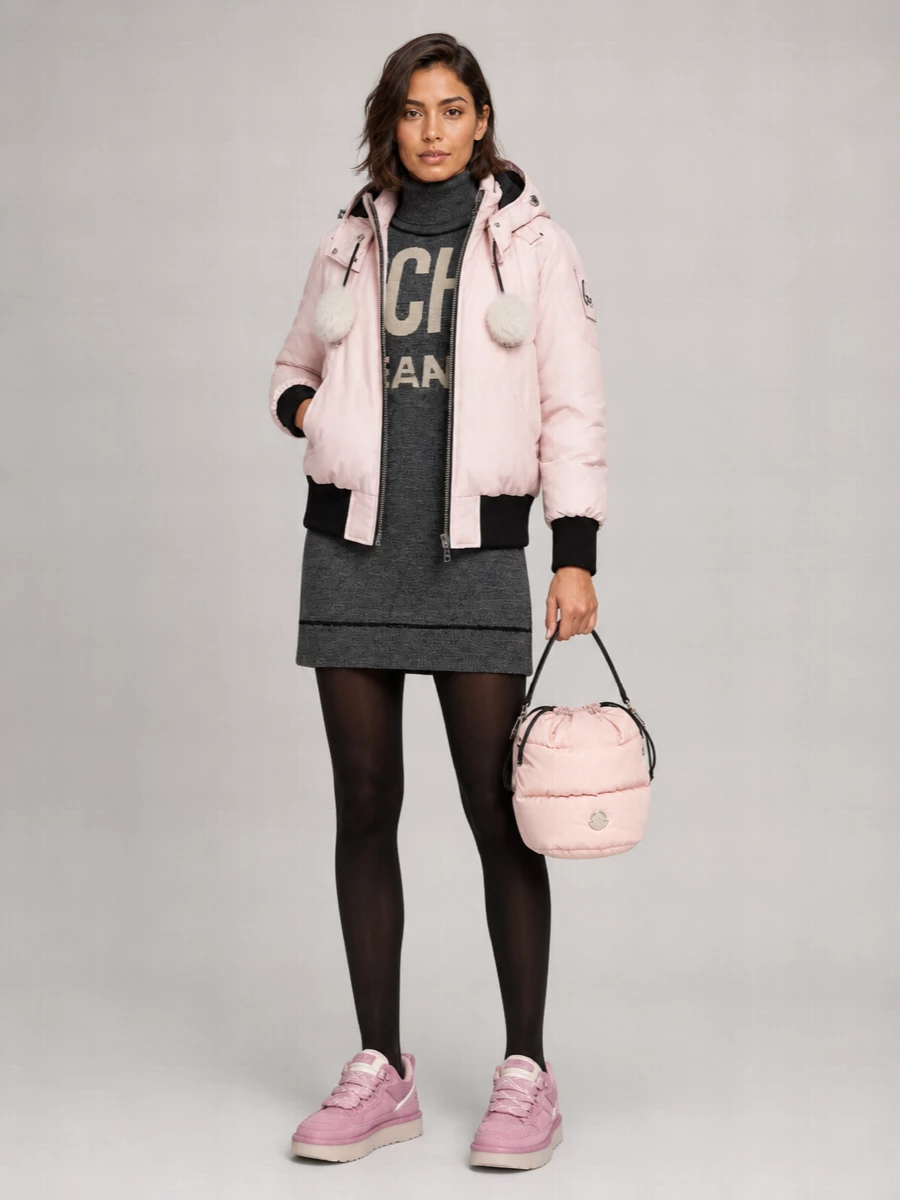 Anchoring the outfit with the sweater dress path keeps the cropped blush bomber as the hero, letting the legs stay clean and elongating instead of adding another padded bottom. The Moschino logo dress and dusty‑pink sneakers lean into a soft, sport‑street palette that feels intentional rather than cutesy, while the blush Moncler bucket bag finishes the outerwear story in a single, tidy colour narrative. It is an easy winter city uniform with enough branding and texture to feel fun but still pulled together.