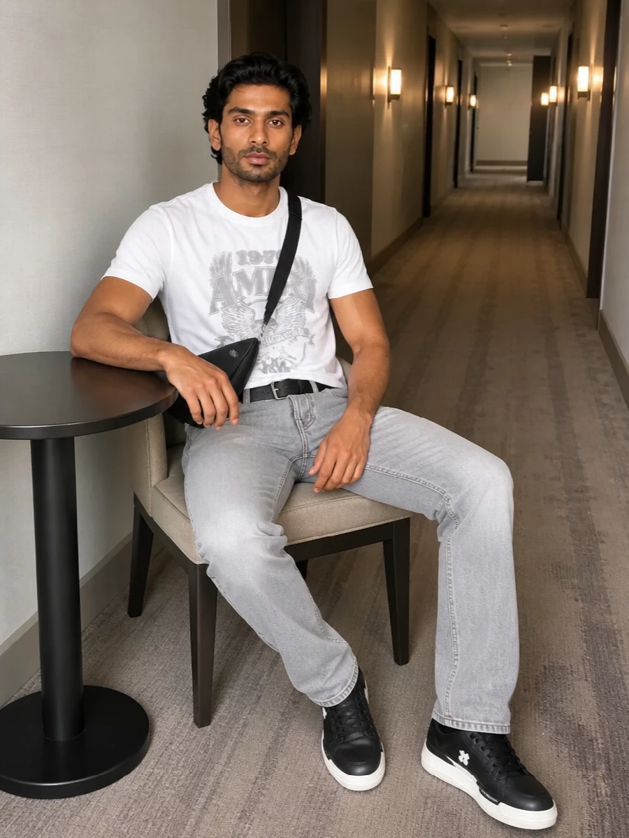 Amiri’s white and grey tee sits over light-grey straight-leg denim for a clean West Coast attitude that feels relaxed but intentional. Chunky monochrome sneakers ground the proportions, while a sleek black Prada crossbody and discreet belt add polished utility without stealing focus from the graphic top. The result is a modern LA street uniform in a tight black, white and grey palette that works from day into night.
