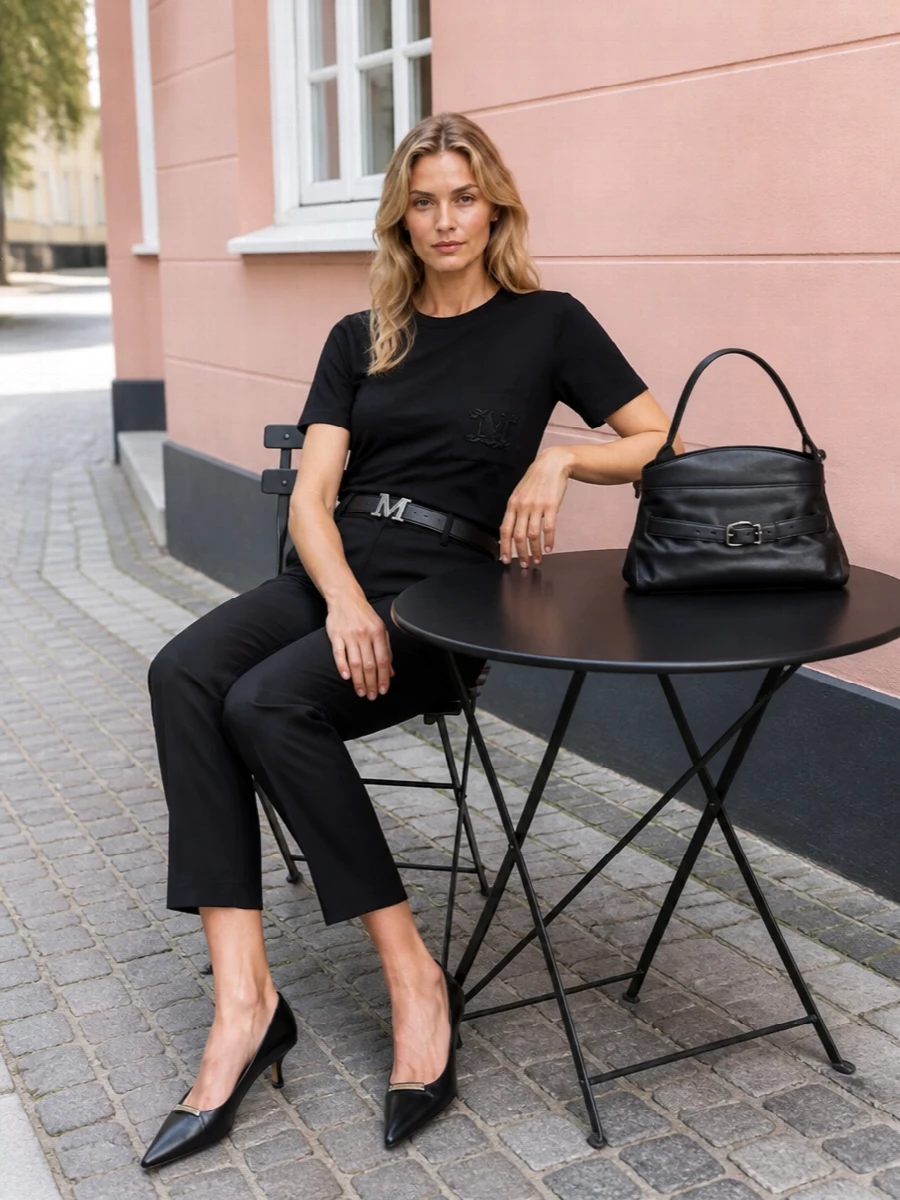 An all-black Max Mara base keeps the focus on clean lines, from the refined tee to cropped tailoring. A low kitten heel and structured top-handle bag sharpen the mood without tipping into stiffness. The slim logo belt quietly connects each element for a cohesive, city-ready uniform.