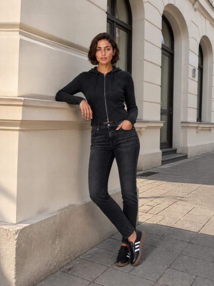This is a clean streetwear city uniform built around the retro Adidas slip-ons, with charcoal slim denim and a cropped knit hoodie keeping the proportions tight and easy. The washed black palette lets the gum sole and three stripes stay graphic without feeling loud. It is relaxed enough for errands but considered enough for casual meetups, and choosing jeans over a dress keeps it grounded in everyday sport.