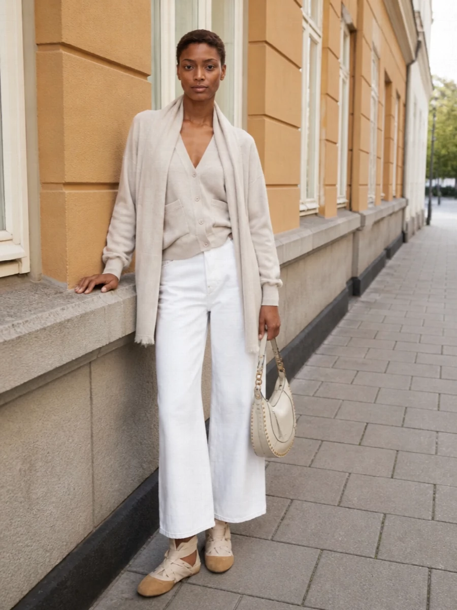 Warm neutrals and soft structure keep this outfit calm yet intentional: the relaxed cardigan meets crisp white wide-leg denim for an easy, elongated line. Cream lace-up ballerinas and an ivory crescent hobo stay within the same sandy spectrum, adding gentle femininity without disrupting the minimalist mood. A gauzy oatmeal stole is the final layer of softness, for days when you want polish that still feels completely unforced.