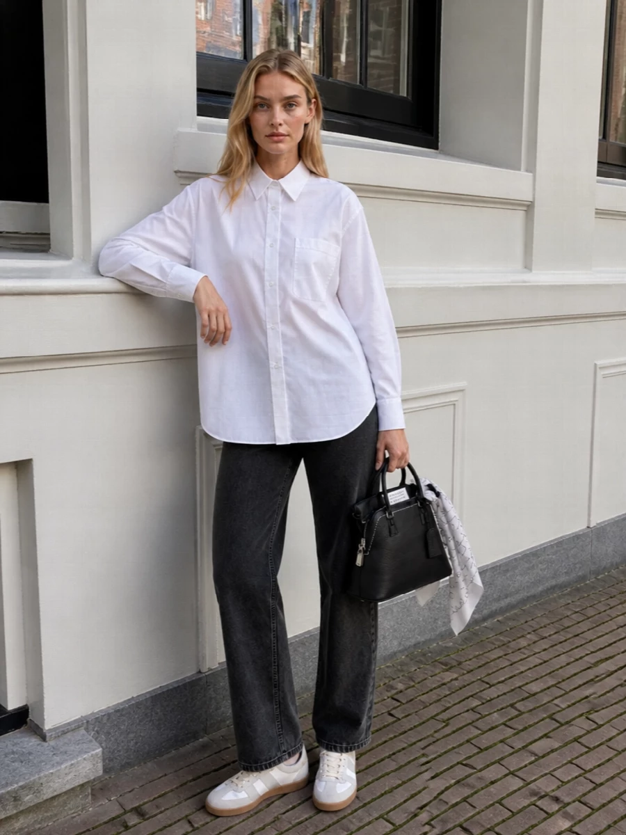 Washed black denim and a sheer, longline white shirt create a monochrome uniform that feels both precise and slightly undone. Iconic white gum-sole sneakers keep the mood relaxed, while the structured black top-handle bag and sketch-like silk scarf add just enough polish to make it city-ready from morning to late afternoon.
