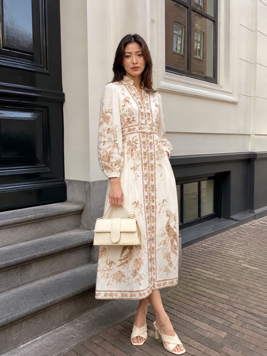 Zimmermann’s embroidered ivory midi is styled tonally with buttercream Bottega mules so the birds and florals stay center stage. A sculpted Jacquemus mini top-handle repeats the soft neutral palette, giving the romance a polished, dinner-ready finish. The result feels boho-leaning yet composed, perfect for candlelit terraces or gallery openings.