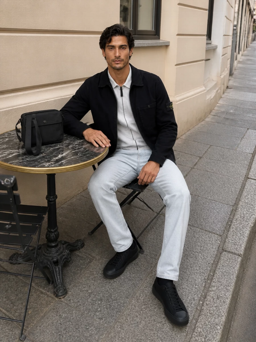 A monochrome Stone Island setup that plays light against dark, pairing a black shirt jacket with cool grey layers and ice denim. The straight leg and low-profile technical sneaker keep everything clean and regular, while the compact crossbody adds just enough utility detail. It feels like easy city uniform territory, precise without trying too hard.
