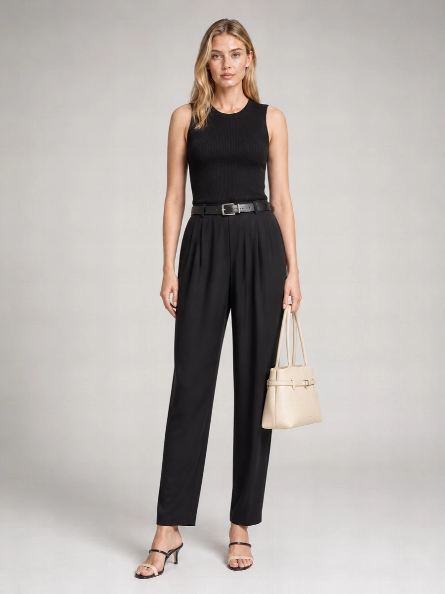 A ribbed black tank meets fluid tailored trousers for a quietly assured all-black column that works from desk to late dinner. The slim kitten-heel mule and structured buttercream shoulder bag introduce lightness and polish, while a clean black belt quietly anchors the proportions. It is a modern, minimalist way to do Italian refinement without feeling overdone.