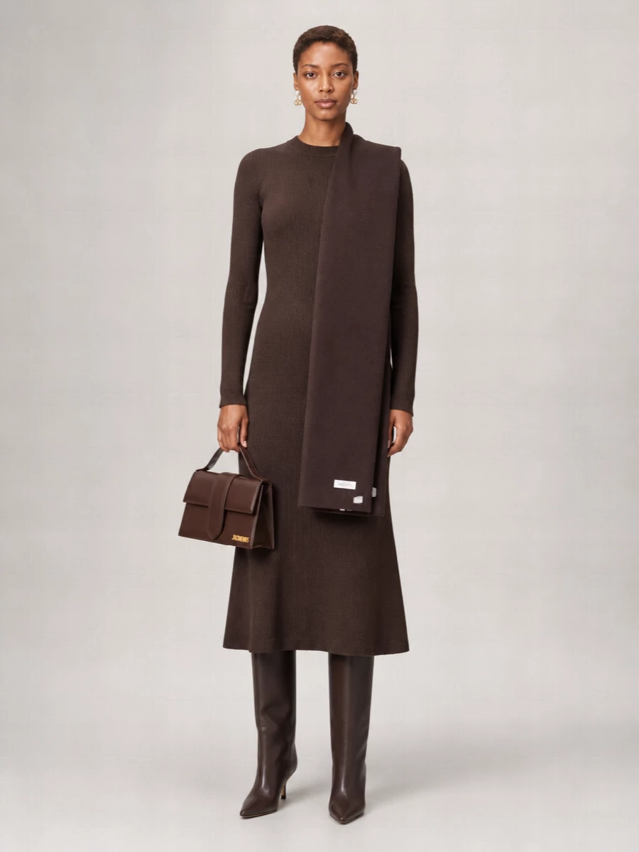 A chocolate tonal story that reads calm and precise, with the knit dress and sleek knee boot creating one long, uninterrupted column. The structured top‑handle bag and quiet pearl studs add definition without disturbing the softness, keeping the outfit ready for anything from office hours to intimate dinners. It is minimal, warm and assured, relying on rich browns and clean shapes rather than overt detailing.