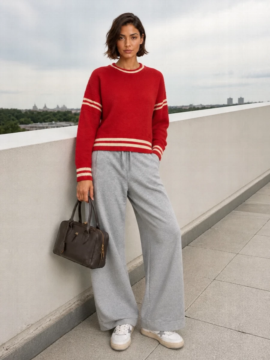Crimson varsity energy sits on soft heather-grey volume for a sporty, relaxed take that still feels considered. Neutral sneakers keep the palette calm, while a structured chocolate top-handle adds just enough polish. The whole outfit reads easy and modern, ideal for city days when you want comfort with a focused color story.