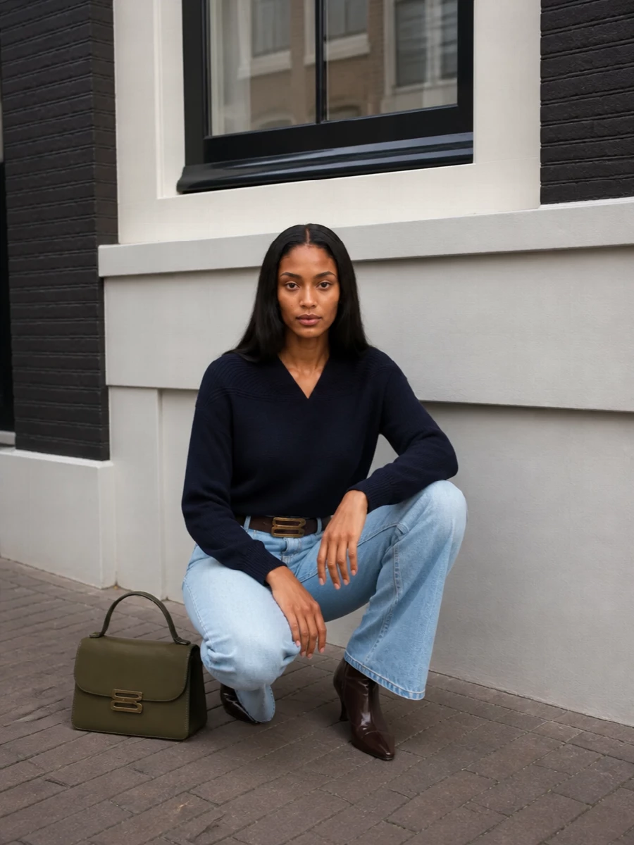 Soft blue flares meet a sculpted navy knit for a pared back, leggy silhouette with just enough structure. Chocolate leather at the waist and ankle grounds the light denim, while an olive top handle keeps the finish quietly intentional. The result is a polished city outfit that moves easily from morning errands to dinner without ever feeling overdone.