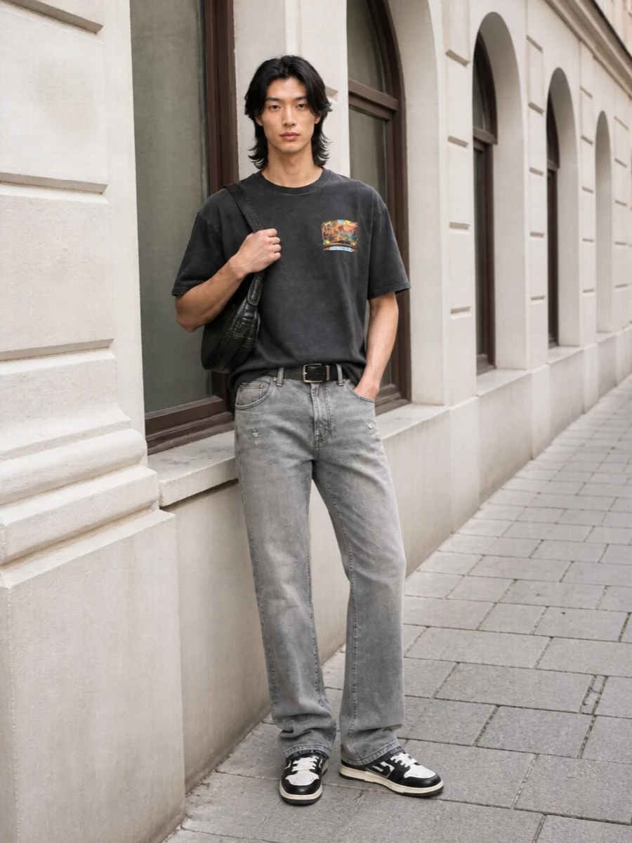 Washed greys and blacks keep this Amiri tee grounded in a tight, modern street palette, with straight-leg denim giving just enough ease through the leg. Graphic paneled sneakers echo the tee’s attitude at ground level, while a compact leather shoulder bag and clean hardware belt sharpen the finish for city days and late-night runs alike. The result is relaxed but deliberate, all about considered fades, subtle distressing and strong details in a strictly monochrome story.