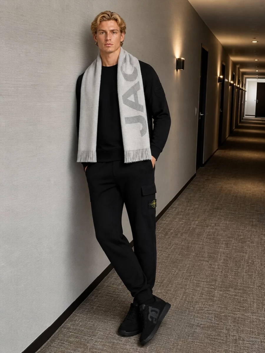 A black-on-black Stone Island base keeps everything sharp and unfussy, letting the compass badges do the talking. The sleek Dolce&Gabbana runners and nylon backpack lean into a functional city mood, while the pale grey scarf softens the palette just enough for depth. It is a clean, technical street uniform that moves easily from commute to weekend without ever feeling over-styled.