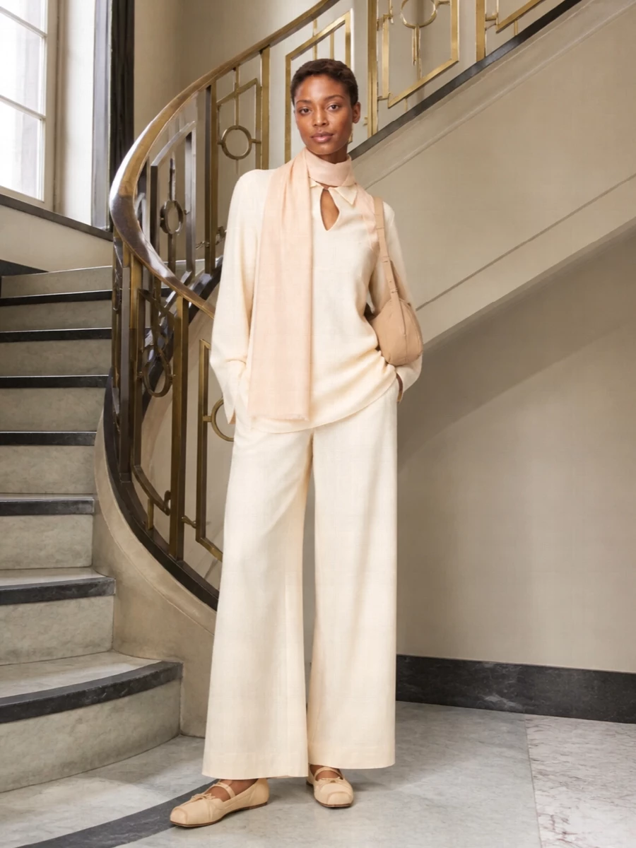 A tonal cream column sets a calm, quietly luxurious mood, the longline tunic skimming over wide-leg trousers for an elongated, easy silhouette. Butter-beige flats keep the line soft and grounded, while a padded camel baguette introduces just enough contrast and texture to feel considered without breaking the serenity. A blush-toned scarf finishes with a gentle, almost weightless layer that suits slow mornings, travel days or low-key dinners alike.