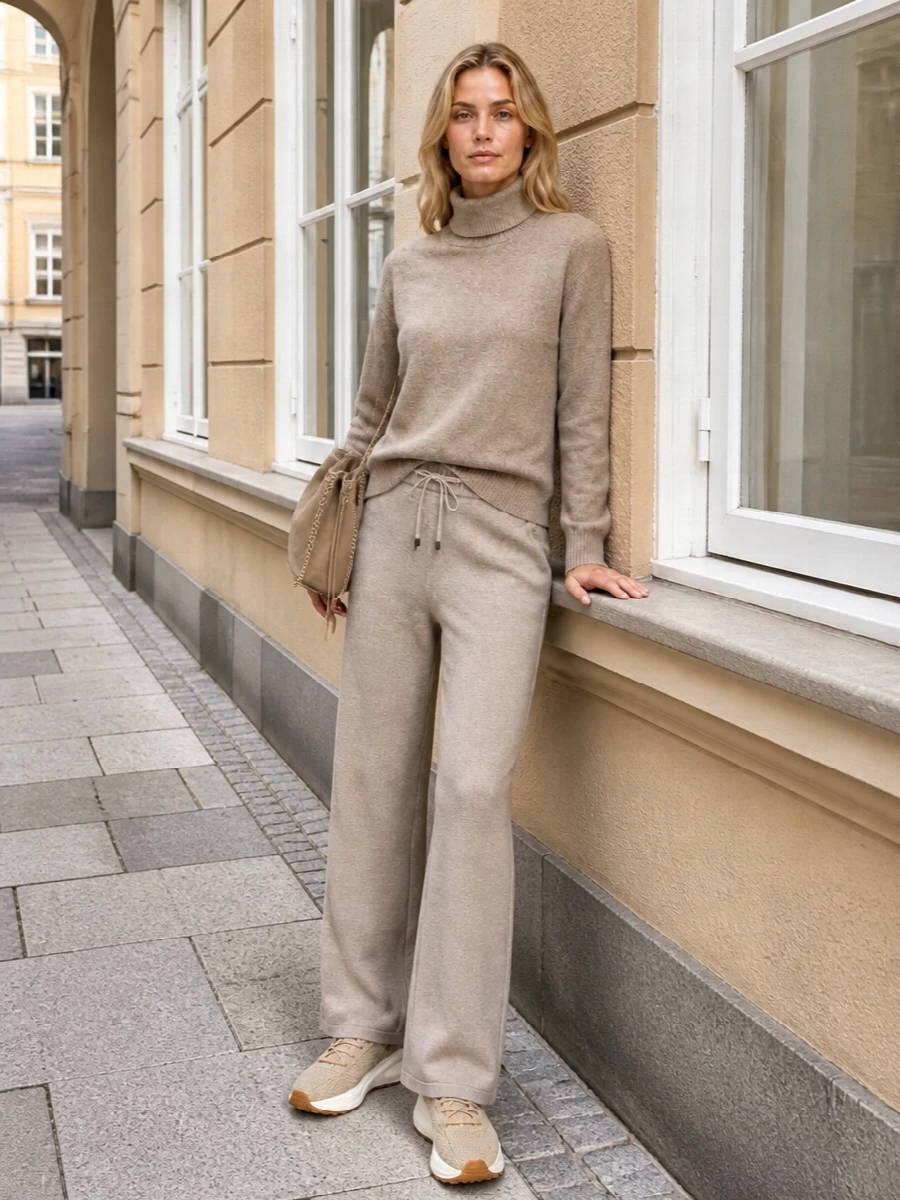 Soft taupe-on-beige layers keep this knit set calm and intentional, with the relaxed turtleneck echoing the trouser’s ease. The sand-toned sneakers keep things modern and mobile, while the suede bucket and stone scarf add just enough texture to feel considered without breaking the palette. Ideal for days when you want loungewear comfort that still reads quietly composed in the city.
