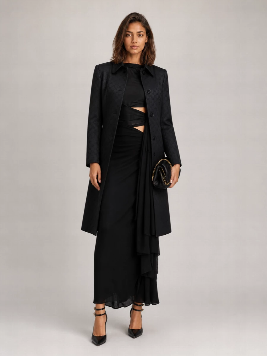 An inky one-shoulder gown stays centre stage, framed by sharply cut black pumps and a soft sculpted clutch that reads like folded satin. The palette is deliberately monochrome so the cut-outs and drape do all the talking, giving a quietly decadent evening presence that feels cinematic without shouting. Finish with barely-there jewellery in silver or white gold to keep the mood refined and nocturnal.