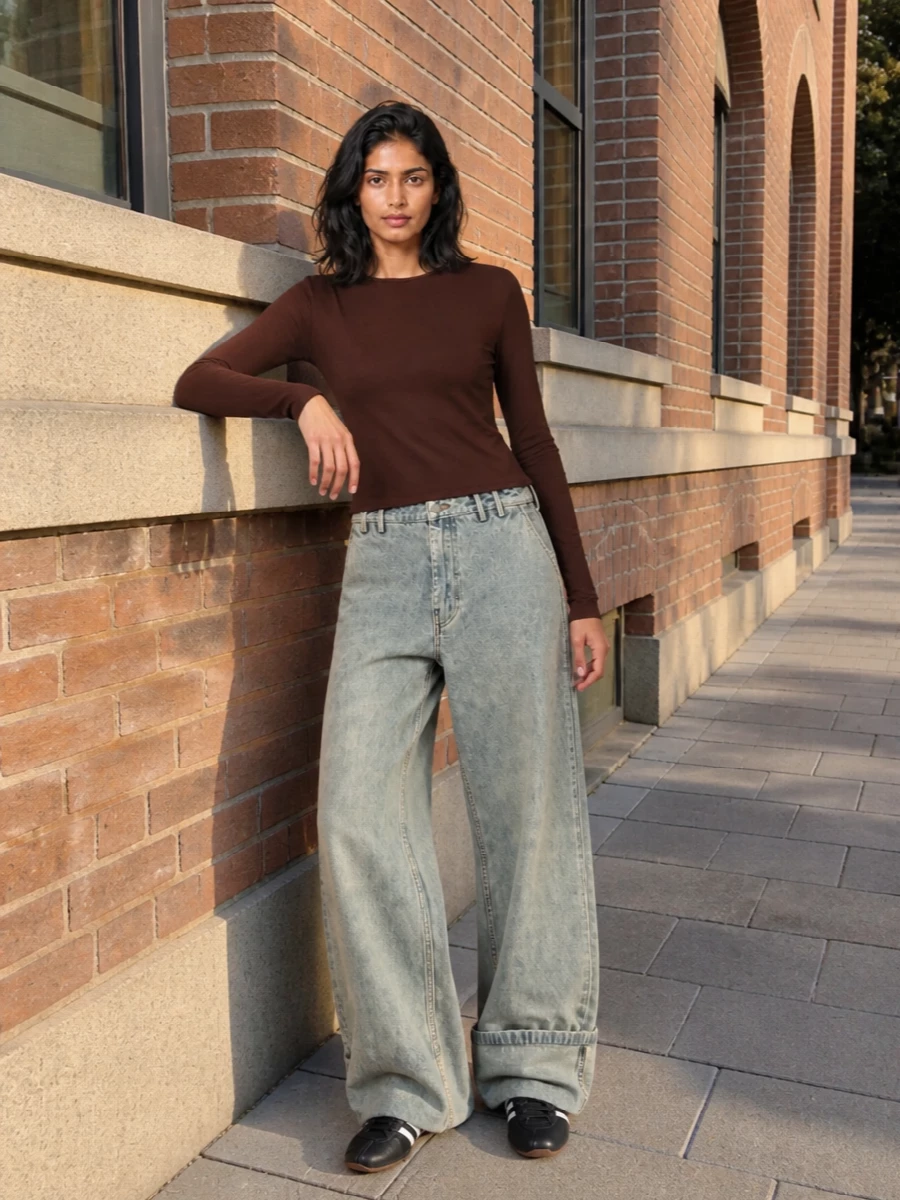 A rich chocolate base meets slouchy, ultra-wide denim for a clean street take on neutrals. Black details in the sneakers and hobo bag tighten the palette and give the softness some structure. The result is relaxed but intentional, made for all-day city movement without feeling loungey.