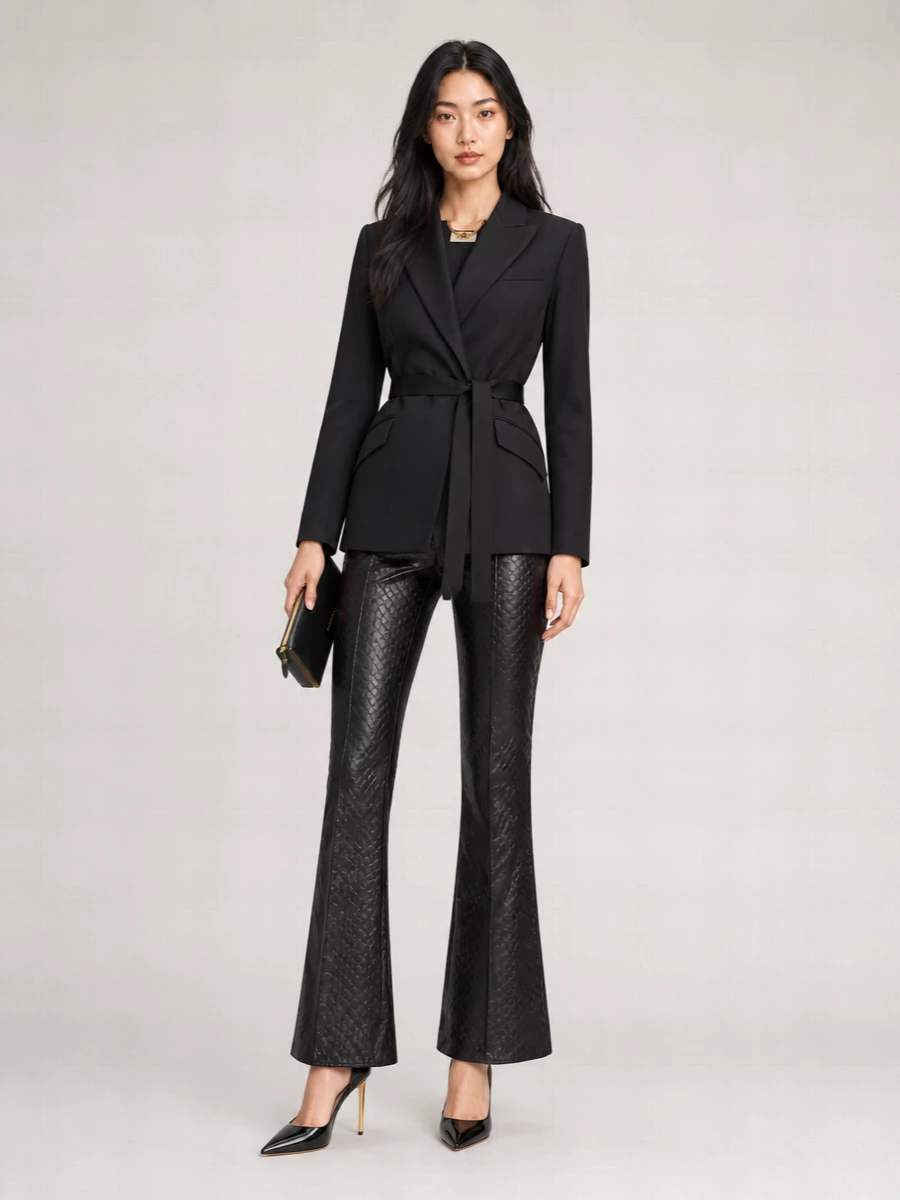 Elisabetta Franchi’s sculpted blazer and high-rise flared trousers create a razor-sharp, hourglass column in jet black with just a flash of gold. Patent Tom Ford heels and a slim framed clutch keep the mood decisively nocturnal, letting the geometric texture and tailoring do the talking. The discreet Prada belt simply locks in the waist, refining an all-black evening ensemble that feels powerful and seductive without excess detail.