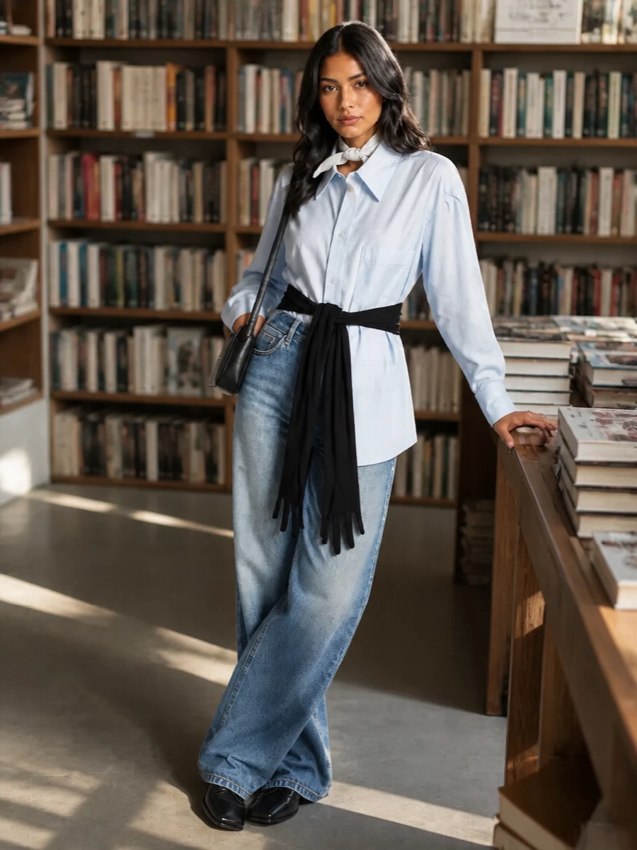 A conceptual take on denim-on-daywear, this pairing keeps the sculptural waistband grounded with a pale blue Margiela shirt cinched in black. Sharp black flats and a slim black shoulder bag streamline the wide leg so it reads intentional and clean rather than casual. A whisper of white silk at the neck or bag softens the graphic contrast while staying firmly in a minimalist, street-leaning register.