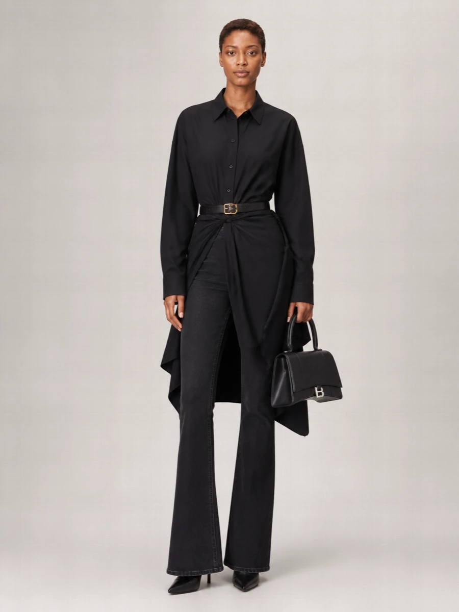 An all-Balenciaga study in proportion, this pairing leans into a long, lean black column, with flared denim grounded by a sculpted, knotted shirt. A razor-sharp sock boot and structured top-handle bag keep the mood precise and modern, while a slim belt just hints at hardware without disrupting the quiet, monochrome palette. It reads as city-ready and confident, minimal on color but rich in cut and structure.