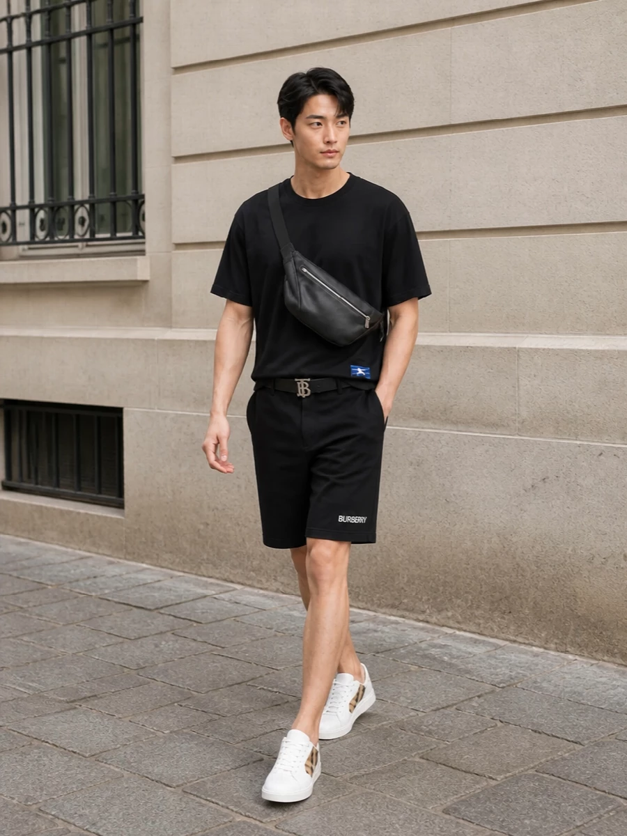 This look centres on an oversized black Burberry tee and black chino shorts for a quietly elevated, monochrome summer uniform. Clean white Burberry sneakers and a sculptural black leather crossbody bring polished contrast and structure, while the slim TB belt adds just enough hardware detail to keep the silhouette refined but still resolutely off-duty.