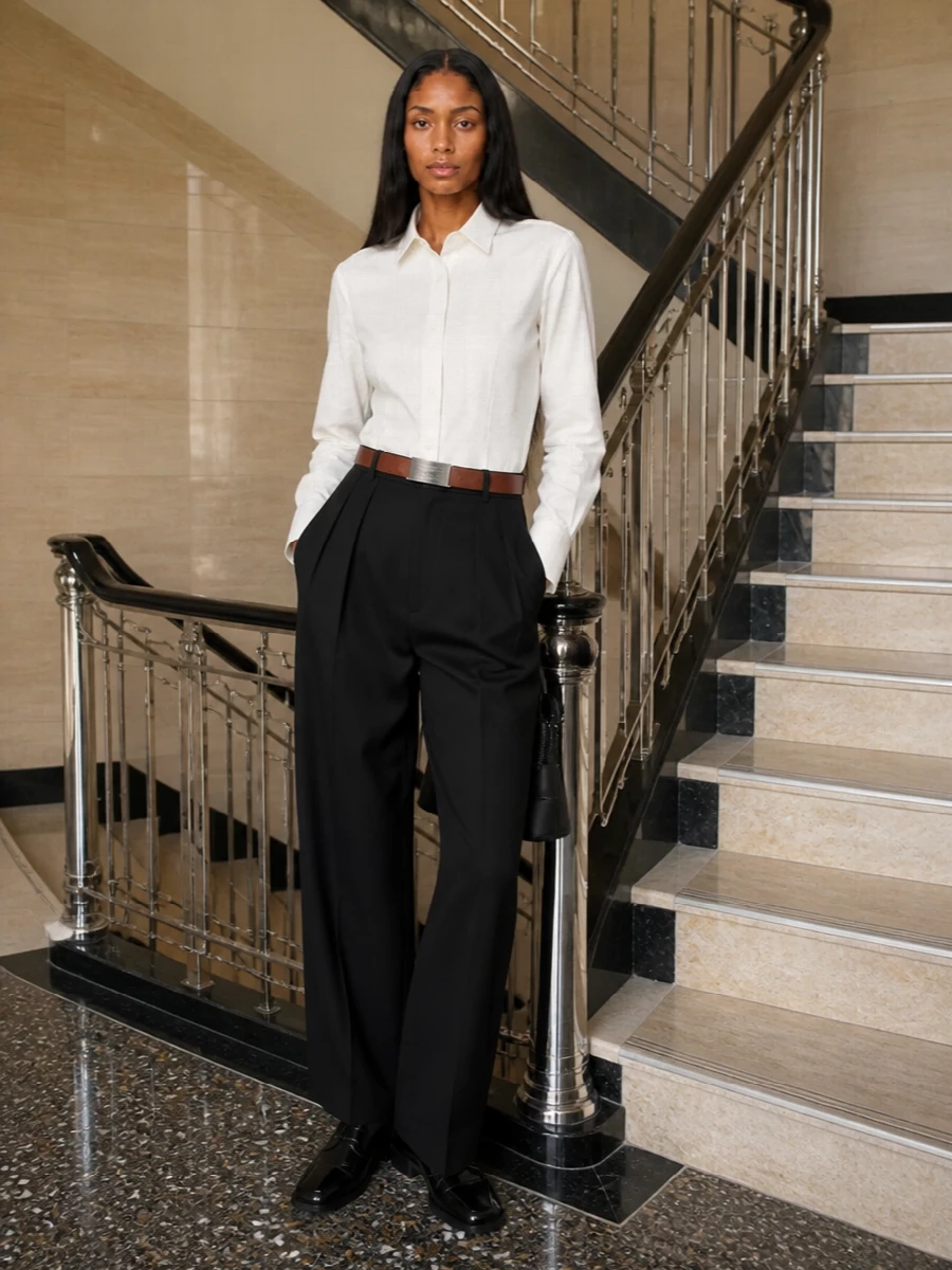 An ivory Margiela shirt meets high-waisted black wide-leg tailoring for a long, precise line that feels calm and assured. Polished derbies and a structured top-handle bag keep the mood disciplined yet quietly subversive, while a clean belt sharpens the waist without disturbing the minimalism. It is boardroom-ready but still reads like insider Margiela, not generic office wear.