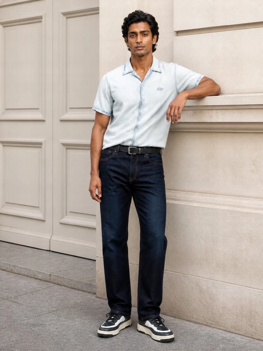 Dark indigo straight-leg denim anchors the outfit, paired with a sun-faded short-sleeve denim shirt that lightens the palette and leans into Diesel’s casual attitude. Charcoal and white sneakers keep the energy urban and easy, while the indigo-and-tan tote and clean black belt pull in subtle preppy structure so it still feels considered for city days or casual Fridays.