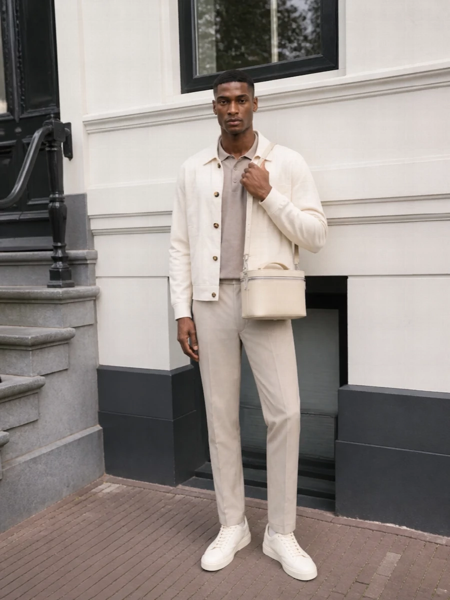 Ivory, cream and light beige sit together here in a calm, tonal story that feels refined without trying too hard. The softly structured blouson, knit polo and tailored trouser create a clean column, with suede-textured sneakers and a compact cream crossbody giving quiet detail. It is summer city dressing at its most confident, discreet and comfortable for long days that slide into dinner.