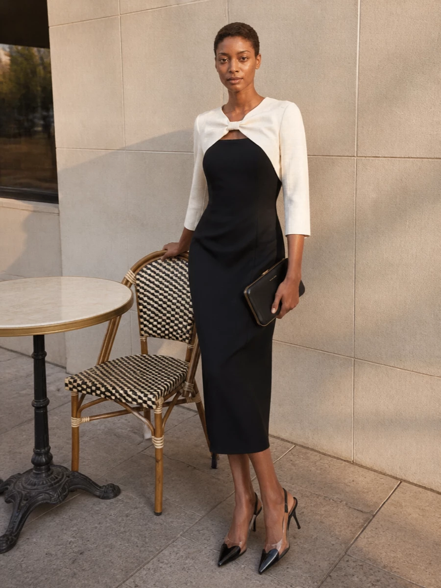 The Alaïa slingback’s black, nude and clear geometry finds its match in Valentino’s black column framed by an ivory bowed overlay, creating a single sculpted line rather than a top and trouser split. Head-to-toe monochrome keeps the mood restrained and quietly luxurious, while the proportions stay clean and vertical for an elongating, gallery-to-dinner silhouette. The sleek Magda Butrym clutch adds a final hit of precise black and gold, echoing the heel’s sharpness without competing with the dress’s couture detailing.