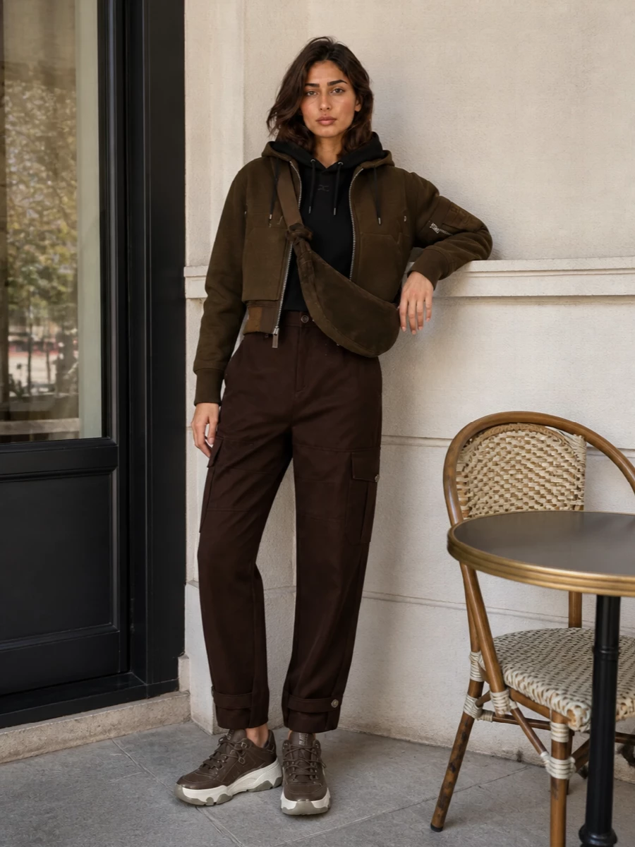 I am keeping this as a trouser-based outfit rather than a dress, because the Sacai bomber’s cropped, tactical cut really comes alive over structured cargos and a slim hooded knit. The all-deep-neutral palette in black and chocolate keeps it cohesive and urban, while the chunky sneakers and sculpted suede bag bring comfort and polish that feel right for long winter city days. It is a grounded, utility-led edit that reads considered without feeling precious, and every piece earns its keep in a real wardrobe.