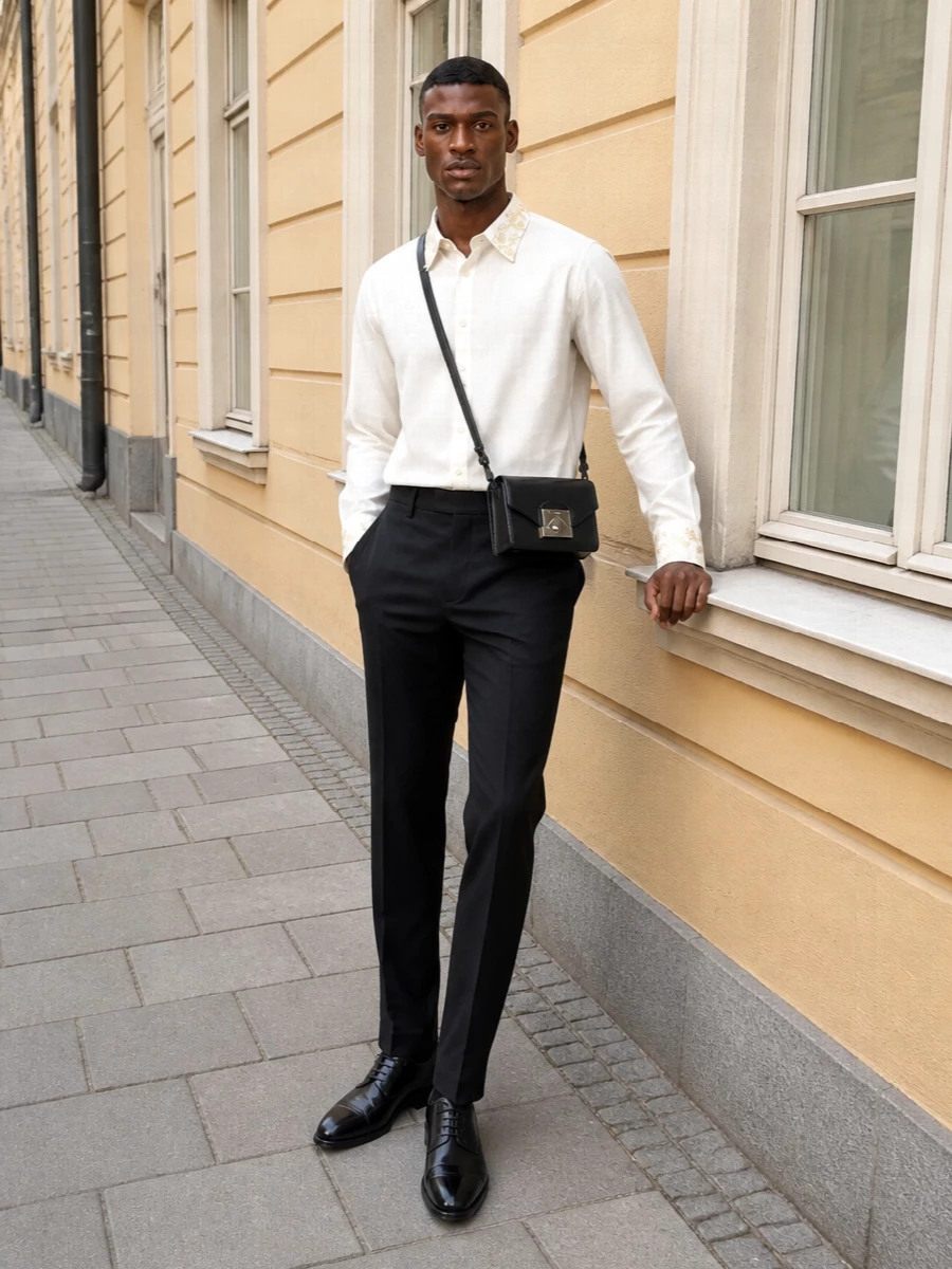 A quietly opulent evening pairing of an ivory embellished shirt with razor-sharp black tailoring puts all the focus on cut, texture and proportion. The straight-leg trouser and high-shine Oxfords create a clean vertical line, while the compact leather crossbody keeps the mood formal but unfussy. It is black-tie adjacent without feeling strict, ideal for intimate dinners, gallery openings or a modern dress-code event.