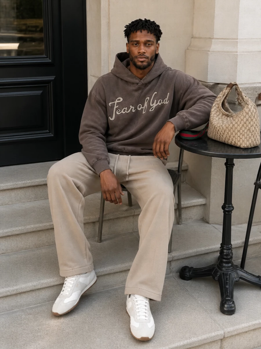 Warm neutrals keep this street-driven outfit calm, with the washed brown hoodie and camel straight-legs creating a soft monochrome base. Pale Prada sneakers lift the palette just enough, adding a clean, designer edge while staying relaxed. The result feels like polished off-duty, perfect for city days where comfort and quiet branding matter equally.