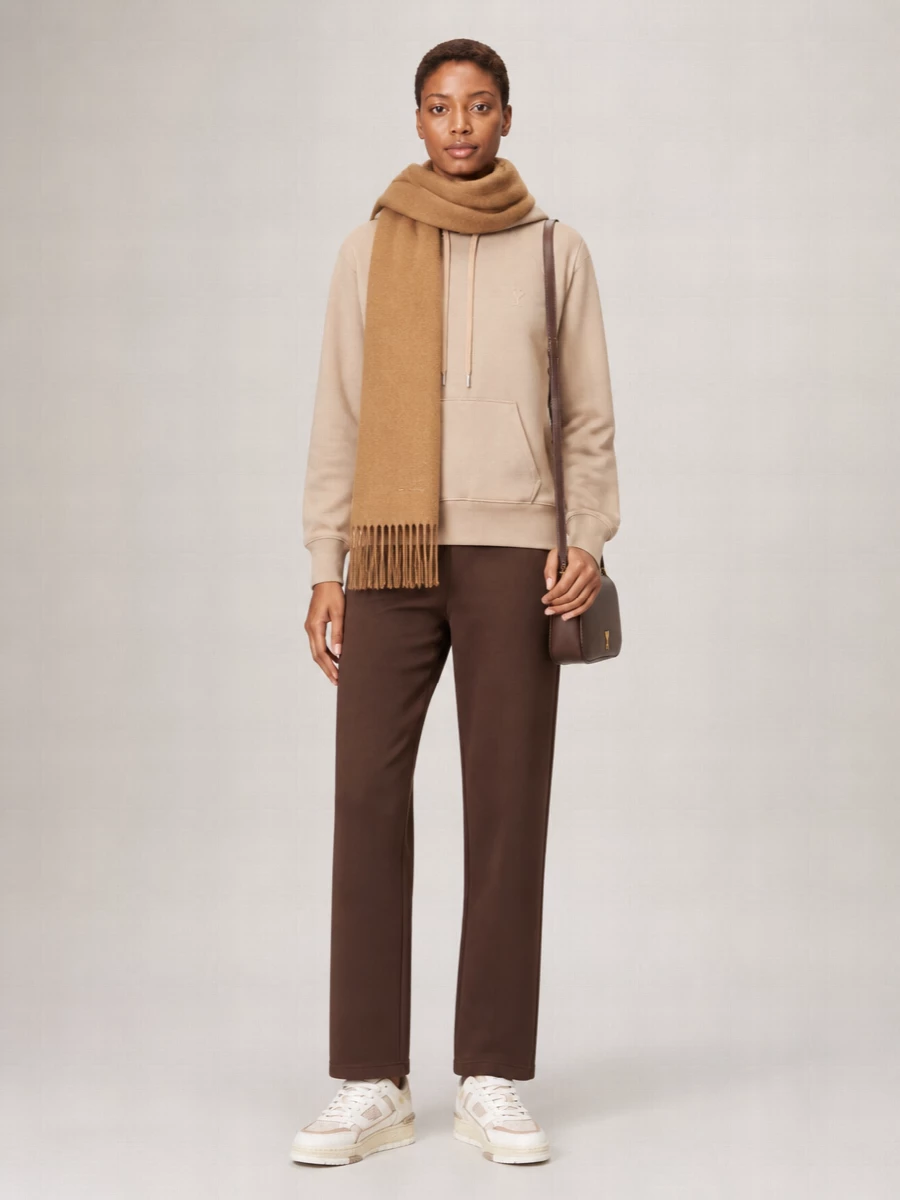 Camel and chocolate sit together here for a calm, grounded off-duty uniform that feels intentionally put together. Relaxed lines on both the hoodie and trousers keep the mood easy, while the tonal sneakers and compact cross-body refine it just enough for city days that drift into low-key evenings. The camel scarf ties the palette together and adds a final layer of softness without crowding the silhouette.