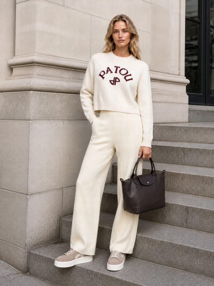Patou’s ivory logo knit pairs with the buttercream wide-leg trouser for a tonal, cocooned take on preppy that still feels precise and graphic. Taupe sneakers keep the silhouette relaxed and modern, while the structured tote adds just enough formality to carry this from errands to casual meetings.