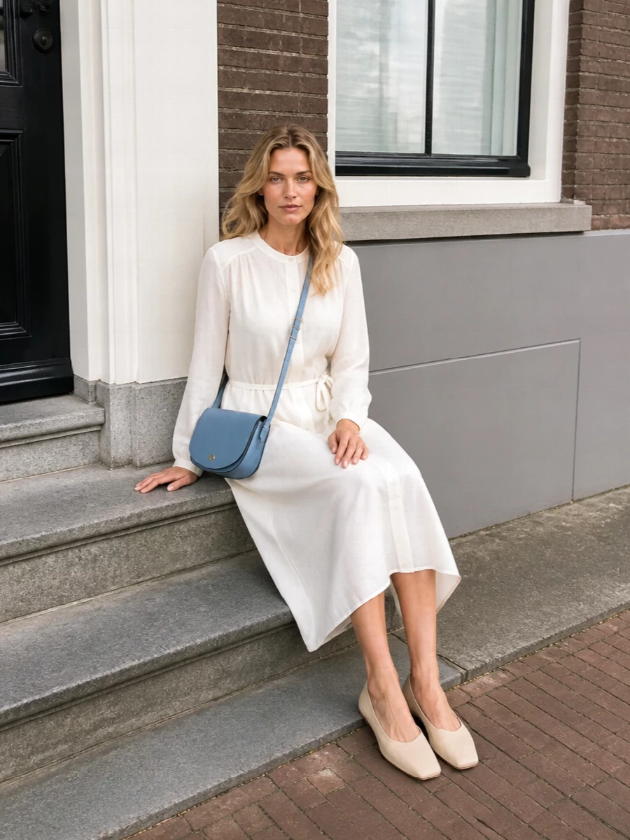 I chose the dress route to keep the outfit as clean and low-effort as the bag, letting one fluid shirt dress handle both structure and ease. The ivory midi and buttercream flats create a calm, elongated column that feels polished but not stiff, so the dusty blue crossbody reads as a soft, modern accent rather than one more competing element. It is an easy city uniform for warm days when you want to look considered without adding extra pieces or colour clashes.