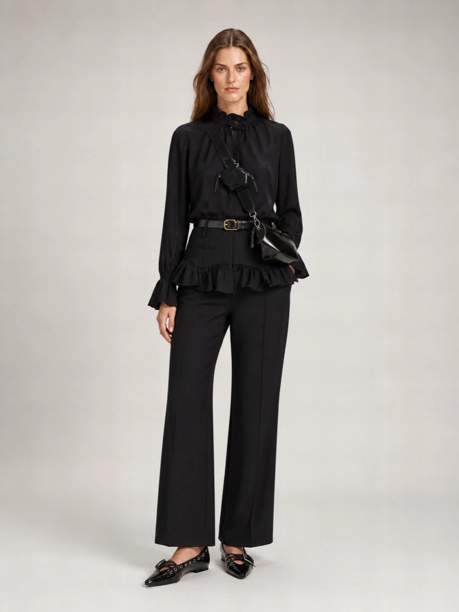 Head-to-toe black keeps the ruffled Ganni trouser feeling sleek rather than sweet, with the fluid high-neck blouse bringing softness above the structured waist. Patent mules and a sculpted cross-body add just enough attitude and shine, while a slim belt quietly sharpens the high waist. It is a romantic yet precise city outfit that moves easily from late office hours into night plans.