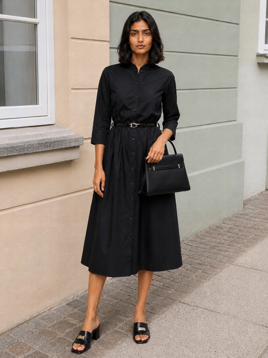 A sharply defined waist and clean black accessories keep the shirt dress feeling intentional rather than easy. The block-heel slide and structured top handle make it ready for office hours that drift into low-key dinners. Silver hardware ties everything back to the dress’s buttons for a quiet, pulled-together finish.