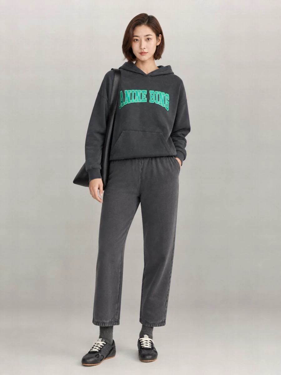 Washed charcoal on charcoal keeps this Anine Bing hoodie and Entire Studios jogger pairing easy, graphic and quietly considered for off-duty days. Chunky-panel Axel Arigato sneakers and a slouchy black Ami shoulder bag lean into city practicality without breaking the minimalist line. Logo-marked charcoal socks are the small branded hit that finishes the palette without shouting.