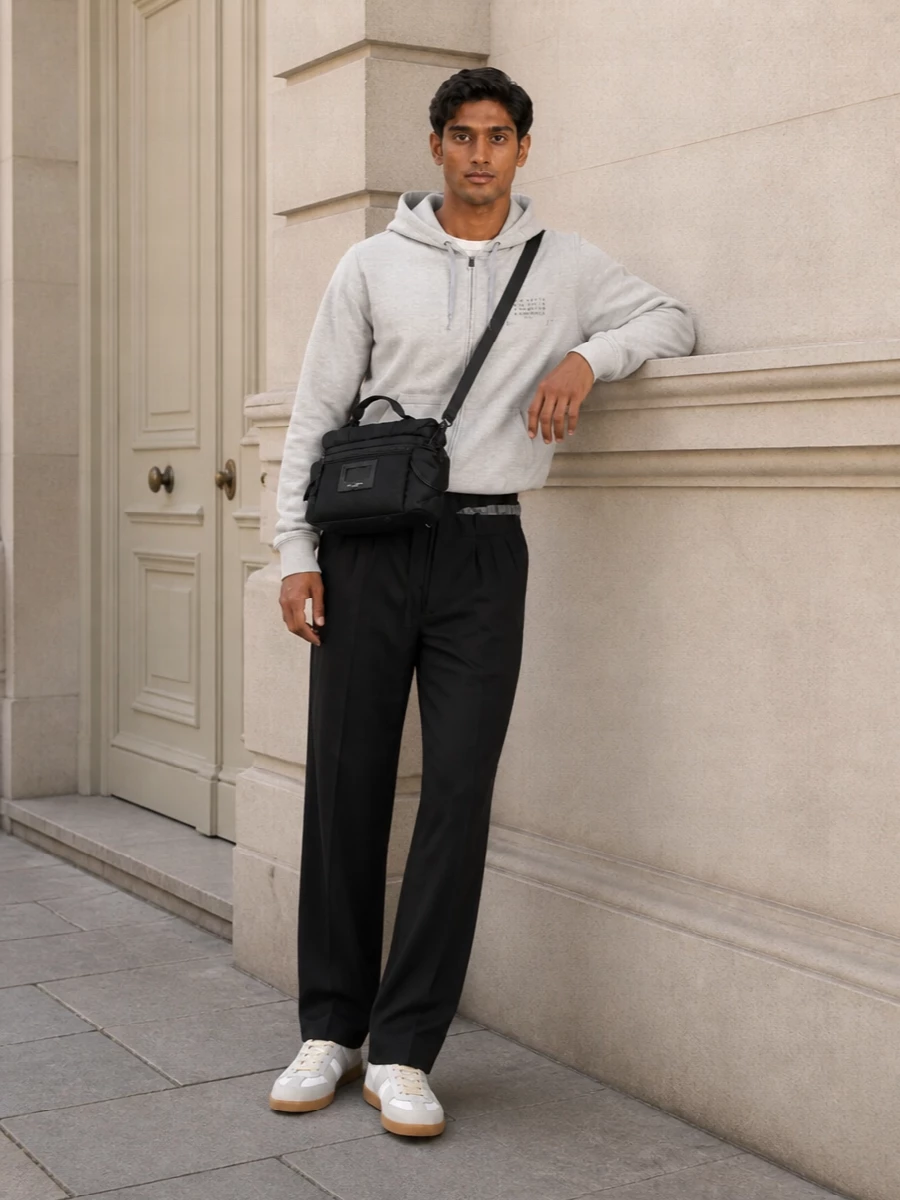 Light grey fleece up top with a tailored drawstring trouser in black creates a calm, monochrome base that feels precise but off duty. The off white low top breaks the darkness just enough, keeping everything clean and grounded. A structured black crossbody sharpens the mix so it reads considered from coffee runs to low key dinners.